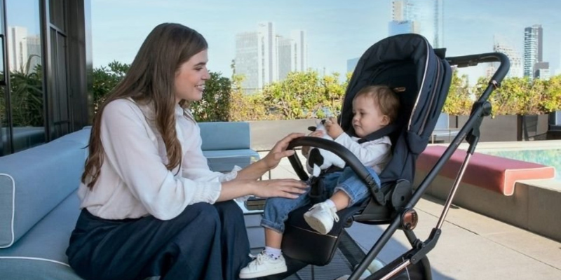Mom kneeing to attend to baby in Peg Perego Stroller