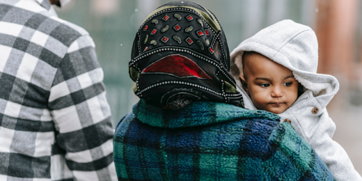Mom carrying baby down city street