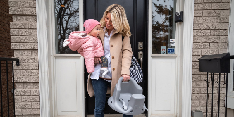 Woman Holding Baby With Booster Floor Seat In Hand