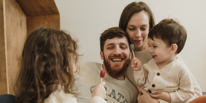 Mom + Dad snuggling with two kiddos eating lollipops