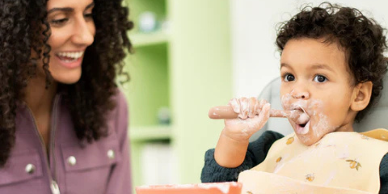 Little boy feeding himself in Nesta 3-in-1 High Chair