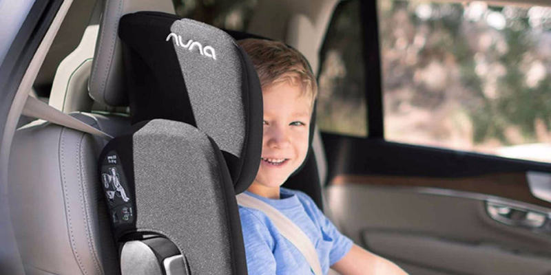 Little boy smiling while sitting in a Nuna AACE booster seat