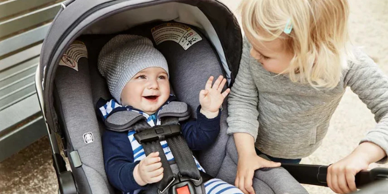 Baby sitting in Nuna PIPA Infant Car Seat beside little girl