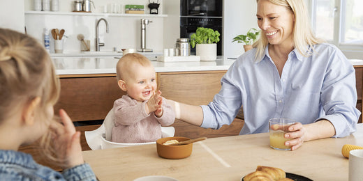 Baby Sitting in the Stokke Nomi High Chair at Table With Woman and Toddler