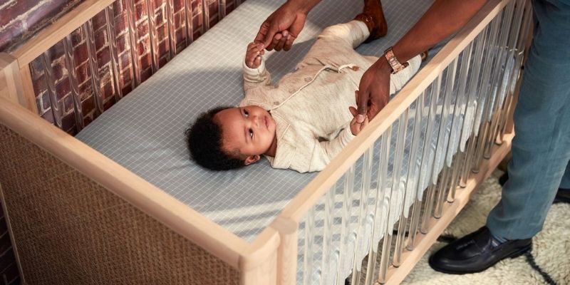 Father putting baby down in Maxi-Cosi Convertible Crib