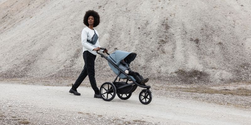 Mother pushing baby on a rough terrain in a Thule Urban Glide 4 Stroller