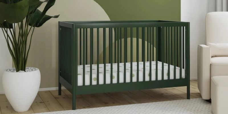 DaVinci Birdie 3-in-1 Convertible Crib in green in a nursery with a glider beside it