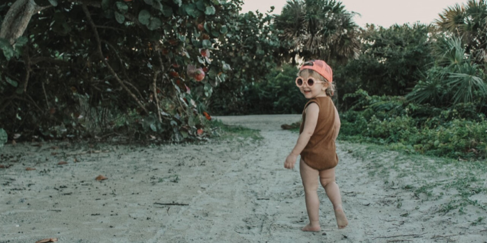 Kid Looking Back and Smiling With Sunglasses and Pink Hat on 