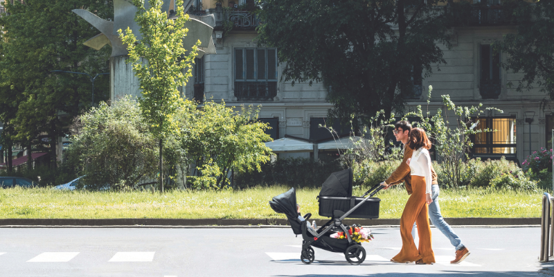 Couple walking across the street with the YPSI Stroller with Bassinet attachment