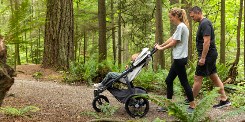 Parents pushing baby down a wooded path in the UPPAbaby RIDGE All-Terrain Stroller