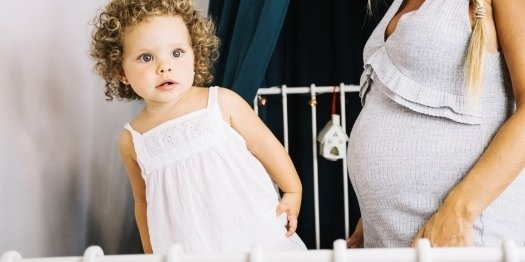 Little Girl With Curly Hair Kneeling on top of Toddler Bed
