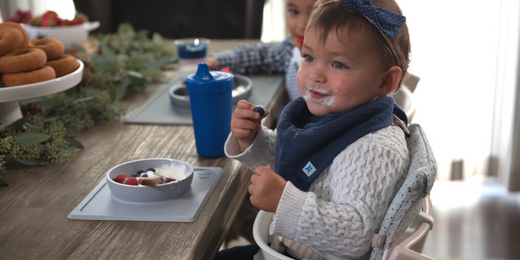 baby sitting in a trip trapp high chair eating berries