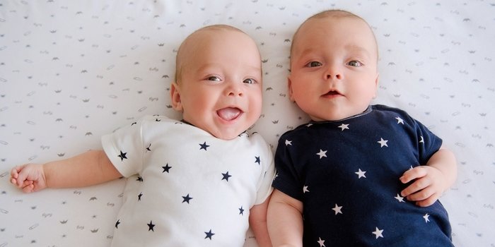 Twin babies in alternate colour matching onesies