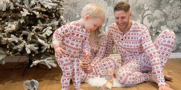 Family Sitting on Floor in Holiday Pyjamas Playing With Blocks