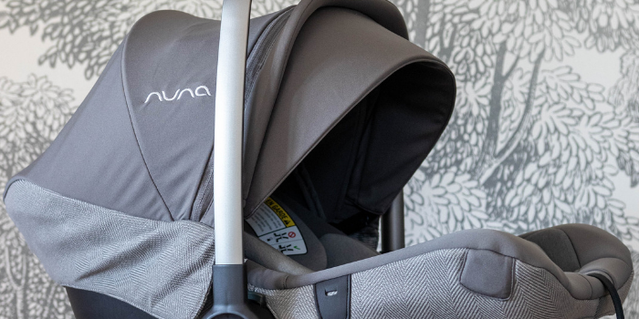 Nuna PIPA Lite LX Car Seat on wooden accent table in front of grey wallpaper