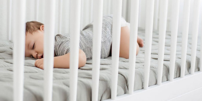 Baby laying on nook crib mattress