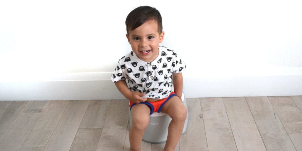 Toddler boy, sitting clothed, on a grey potty