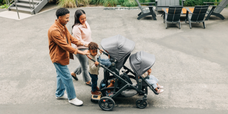 Mom and dad pushing three children in an UPPAbaby Vista V3 Stroller