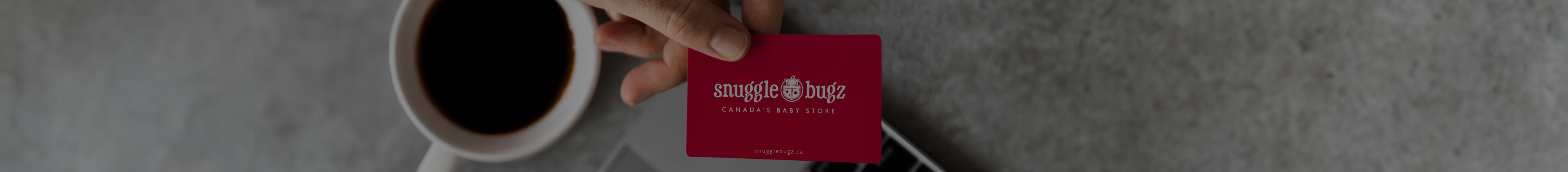 Women on her computer holding a Snuggle Bugz gift card