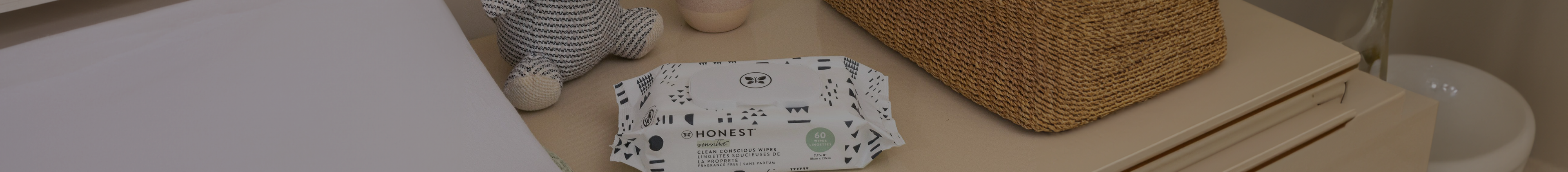 A pack of The Honest Company diaper wipes sitting on a nursery dresser beside change pad