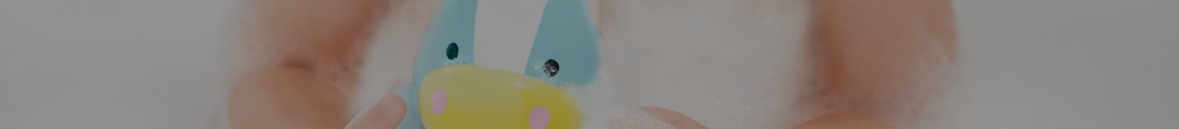 Little girl playing in the bath with a Skip Hop unicorn bath toy